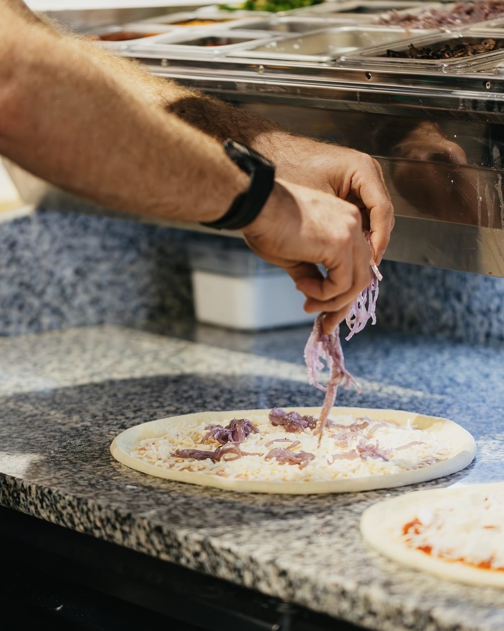 Caramelised onions going onto a white pie